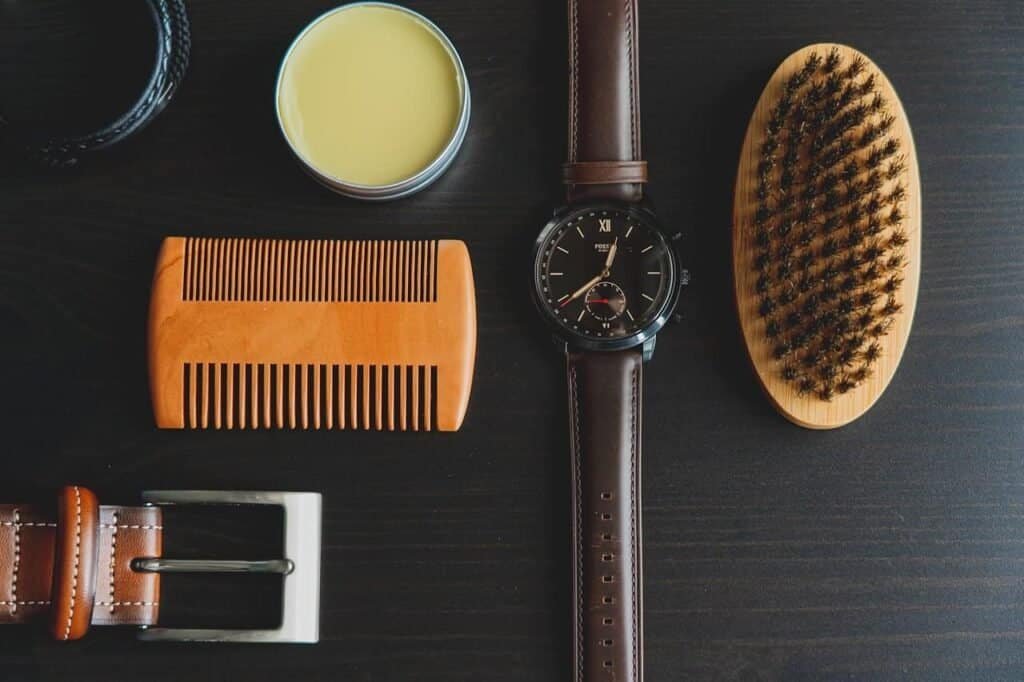 A display of men's accessories including watch, comb, belt, brush and a tin of pomade