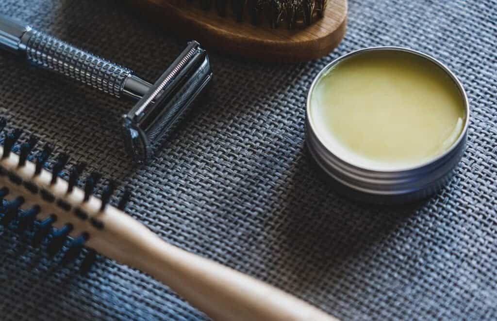 An zoomed image focused on men's grooming tools and products including pomade, razor and hairbrush