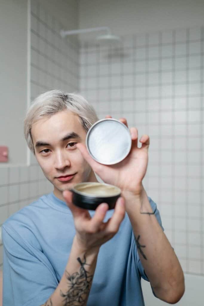 A man holding up a container of hair product